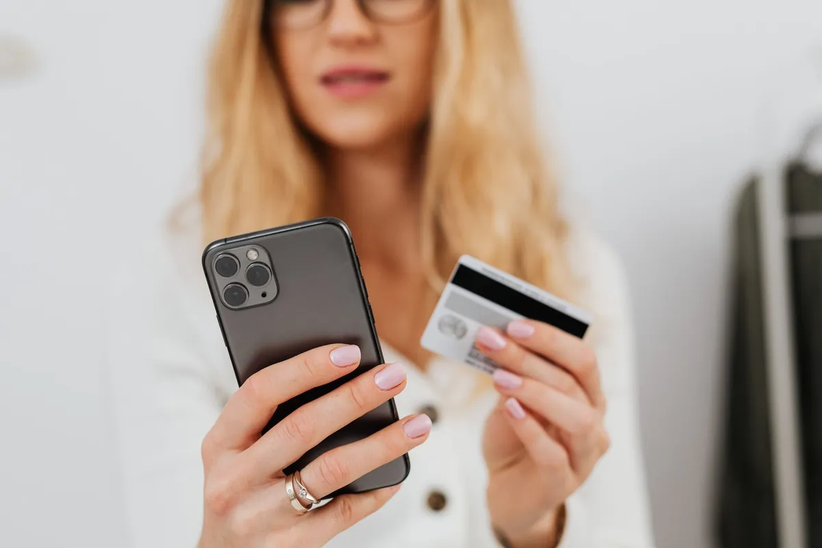 Mãos segurando celular com sacola de compras - loja online integrada ao WhatsApp da Poupar AI